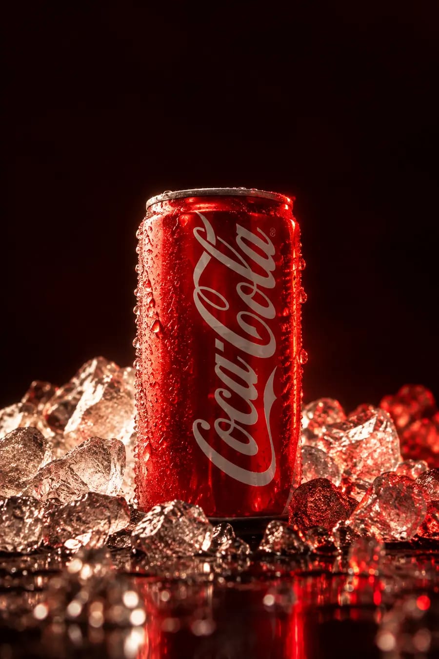 Una lattina rossa con la condensa, appoggiata su ghiaccio tritato.